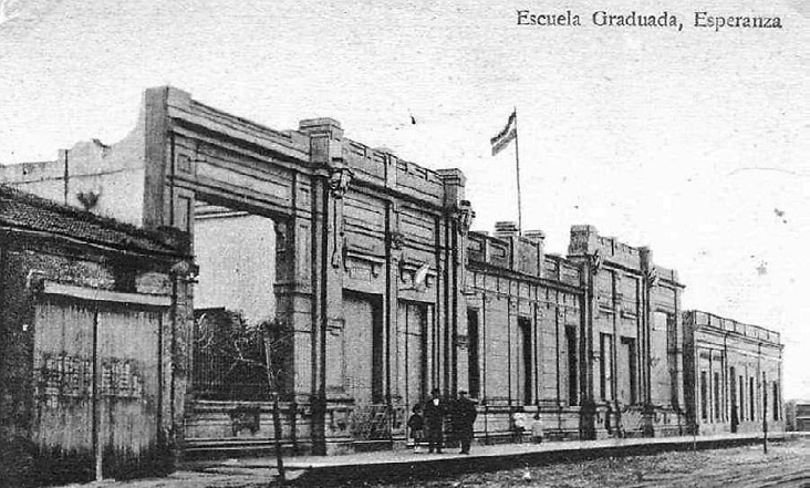 Figura 6. En la imagen se puede ver la entrada principal de la escuela y pegado al edificio educativo se ve una sección del molino con una puerta de madera de doble hoja. Fuente. Museo de la Colonización